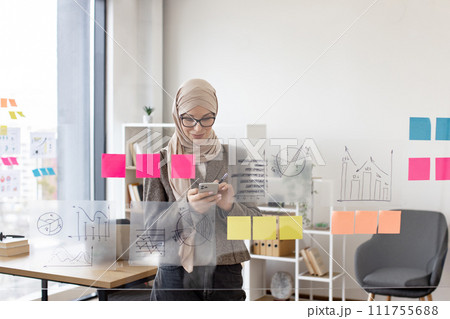 Muslim woman in hijab solving business issues while typing on smartphone. Muslim woman in hijab solving business issues while typing on smartphone. 111755688