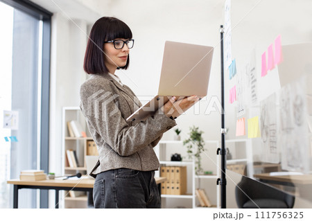 Caucasian woman in formal wear and glasses solving business issues with laptop. 111756325