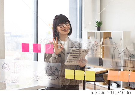 Smiling female employee having video conference at modern office. Smiling female employee having video conference at modern office. 111756365