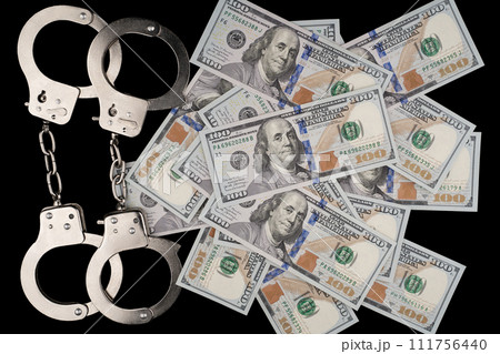composition of 100 dollar bill on black background and police handcuffs 111756440