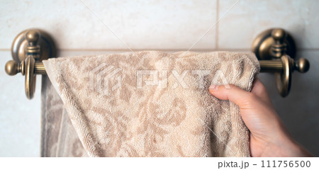 Girl is hanging clean towel on a holder. 111756500