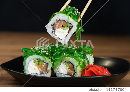 delicious traditional Japanese sushi and rolls on a plate holding chopsticks delicious traditional Japanese sushi and rolls on a plate holding chopsticks 111757004