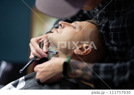a man gets a haircut and a shave in a barbershop a man gets a haircut and a shave in a barbershop 111757030