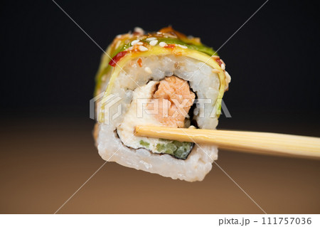 delicious traditional Japanese sushi and rolls on a plate holding chopsticks delicious traditional Japanese sushi and rolls on a plate holding chopsticks 111757036