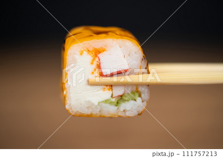 delicious traditional Japanese sushi and rolls on a plate holding chopsticks delicious traditional Japanese sushi and rolls on a plate holding chopsticks 111757213
