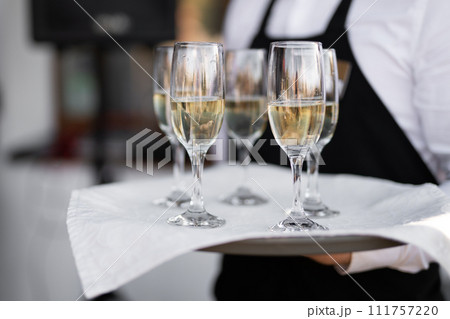 the waiter holds champagne glasses on a tray the waiter holds champagne glasses on a tray 111757220