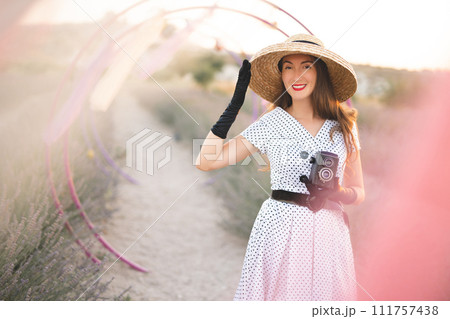 beautiful girl in retro dress and old camera posing on lavender field with scenery beautiful girl in retro dress and old camera posing on lavender field with scenery 111757438