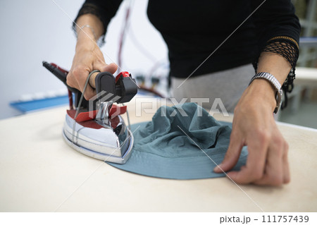a worker irons clothes at a sewing factory a worker irons clothes at a sewing factory 111757439