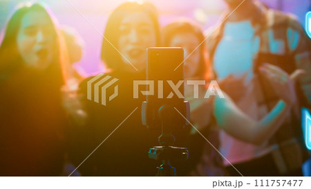 Influencer filming vlog at club party, using smartphone to record video of her and her friends having fun on dance floor. Happy woman enjoying night out clubbing with people, social media. Influencer filming vlog at club party, using smartphone to record video of her and her friends having fun on dance floor. Happy woman enjoying night out clubbing with people, social media. 111757477