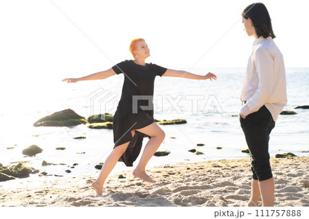 two lovers boy and girl are happy walking and hugging on the sandy beach near the sea. two lovers boy and girl are happy walking and hugging on the sandy beach near the sea. 111757888