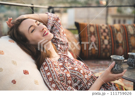 beautiful girl is relaxing with a cup of tea on the sofa in Turkish style and interior beautiful girl is relaxing with a cup of tea on the sofa in Turkish style and interior 111759026