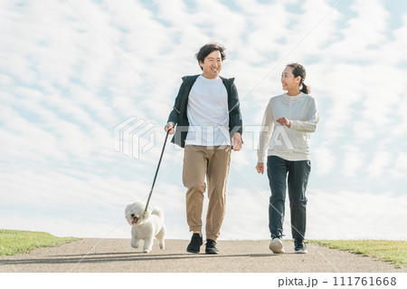 公園で犬の散歩をする家族・夫婦・カップル・男女 公園で犬の散歩をする家族・夫婦・カップル・男女 111761668