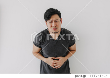 Asian man in black t-shirt feeling sick and stomach ache isolated on white. Asian man in black t-shirt feeling sick and stomach ache isolated on white. 111761692