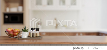 An apple bowl, spice bottles, and a copy space on a wooden kitchen countertop in a modern kitchen. An apple bowl, spice bottles, and a copy space on a wooden kitchen countertop in a modern kitchen. 111762596
