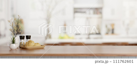 A bread basket, spice bottles, and a copy space on a wooden kitchen countertop in a modern kitchen. A bread basket, spice bottles, and a copy space on a wooden kitchen countertop in a modern kitchen. 111762601