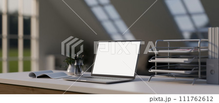 A modern office desk workspace with a white-screen laptop computer mockup and office supplies. 111762612