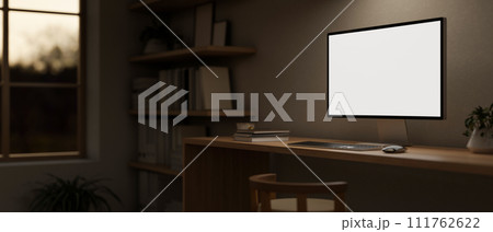 A minimal cosy home office workspace in the evening with a computer mockup on a wooden desk. A minimal cosy home office workspace in the evening with a computer mockup on a wooden desk. 111762622