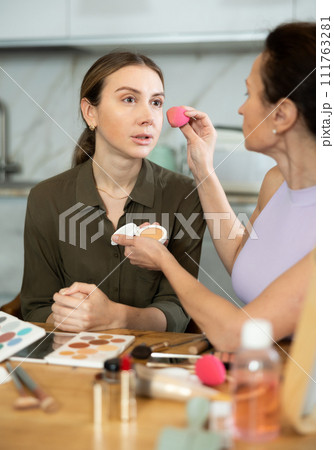 Makeup artist applying foundation to woman face using sponge 111763281