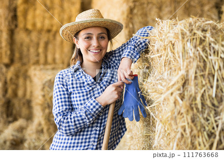 Female farmer posing in barn against the backdrop of hay bales Female farmer posing in barn against the backdrop of hay bales 111763668