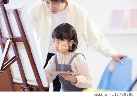 絵画教室　先生の指導を受けながらキャンパスに絵を描く女の子 111768286