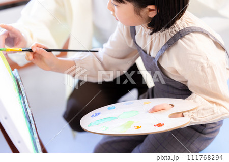 絵画教室　先生の指導を受けながらキャンパスに絵を描く女の子 111768294