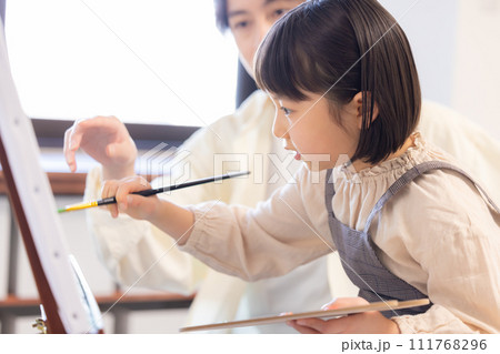 絵画教室　先生の指導を受けながらキャンパスに絵を描く女の子 111768296