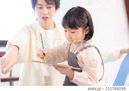 絵画教室　先生の指導を受けながらキャンパスに絵を描く女の子 111768298