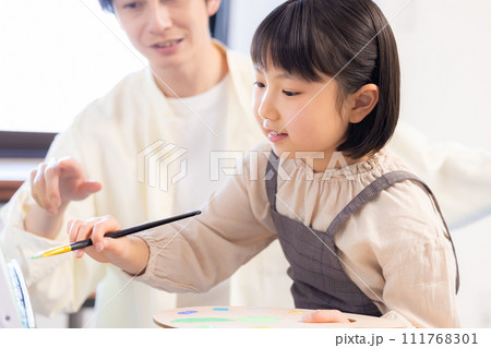 絵画教室　先生の指導を受けながらキャンパスに絵を描く女の子 111768301