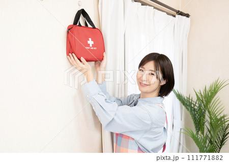 壁に掛けた非常持ち出し袋を持つ女性 壁に掛けた非常持ち出し袋を持つ女性 111771882