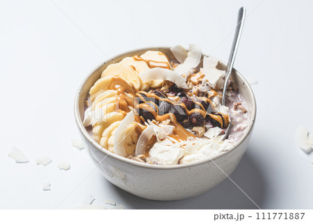 Overnight oatmeal with banana, berries, coconut chips and peanut butter. 111771887