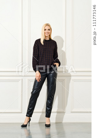 Elegant woman in black outfit against white wall Elegant woman in black outfit against white wall 111773146