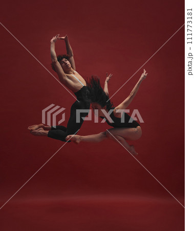 Young man and woman, ballet dancers making creative, beautiful performance, dancing against red background Young man and woman, ballet dancers making creative, beautiful performance, dancing against red background 111773181