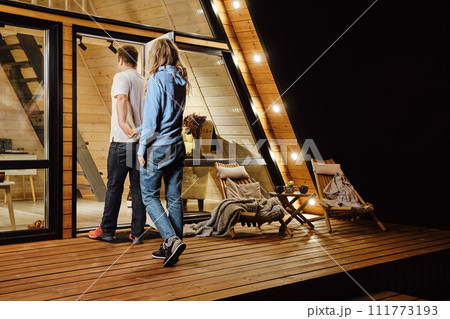 A couple returns to log cabin late at night after a walk outdoors 111773193