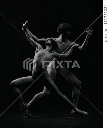 Dynamic artistic pose. Young man and woman, ballet dancers making creative, passionate performance. Black and white 111773224