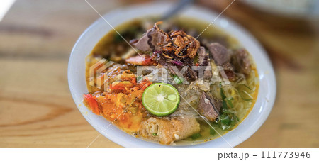 Indonesian style beef noodle soup called soto mie, freshly made soup with vermicelli rice noodle, fried shallots, chilli paste, and fried rissoles Indonesian style beef noodle soup called soto mie, freshly made soup with vermicelli rice noodle, fried shallots, chilli paste, and fried rissoles 111773946