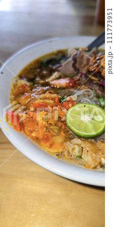 Indonesian style beef noodle soup called soto mie, freshly made soup with vermicelli rice noodle, fried shallots, chilli paste, and fried rissoles 111773951