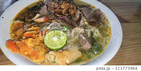 Indonesian style beef noodle soup called soto mie, freshly made soup with vermicelli rice noodle, fried shallots, chilli paste, and fried rissoles Indonesian style beef noodle soup called soto mie, freshly made soup with vermicelli rice noodle, fried shallots, chilli paste, and fried rissoles 111773968
