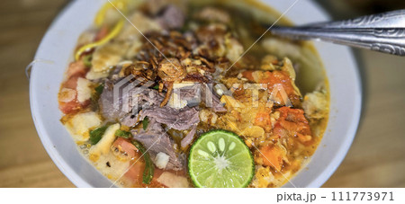 Indonesian style beef noodle soup called soto mie, freshly made soup with vermicelli rice noodle, fried shallots, chilli paste, and fried rissoles Indonesian style beef noodle soup called soto mie, freshly made soup with vermicelli rice noodle, fried shallots, chilli paste, and fried rissoles 111773971