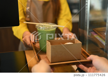 Closeup waitress serving matcha green tea and cake in a cardboard takeaway box to customer 111775426