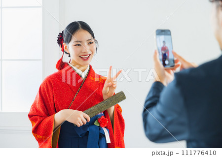 袴の女性の写真を撮る男性 111776410