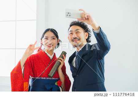 袴の女性の写真を撮る男性 111776418