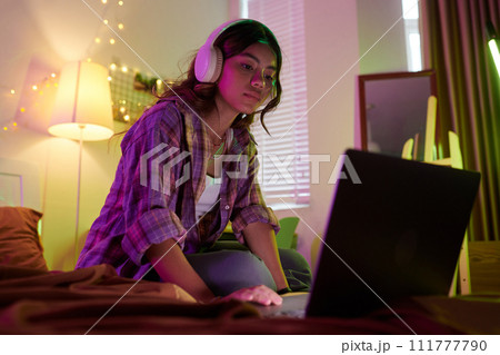 Teenage blogger in headphones editing video on laptop Teenage blogger in headphones editing video on laptop 111777790