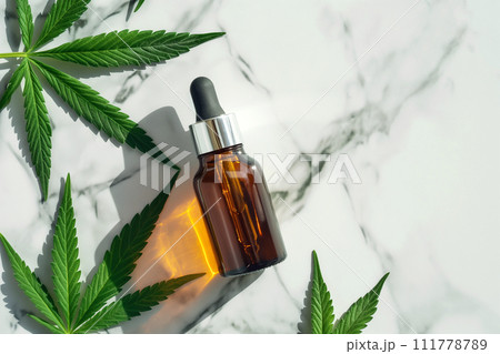 CBD Hemp oil in a dropper bottle. Cannabis oil with Marijuana plants around. Medical marijuana green leaves, alternative medicine. Oil extracts in a bottle, natural treatment, cosmetic component. 111778789