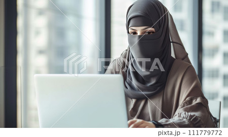 Woman in Niqab Working on Laptop Woman in Niqab Working on Laptop 111779772