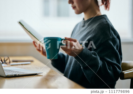 コーヒーカップを持ちながらノートを見る若い女性 111779896