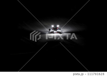 snowcat preparing ski tracks at night 111781628