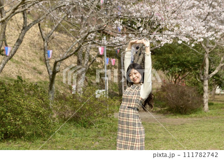 サクラ咲く公園でポーズをとる若くスリムな女性 サクラ咲く公園でポーズをとる若くスリムな女性 111782742