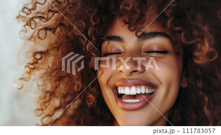 Happy laughing American African woman with her curly hair. Laughing curly woman in sweater touching her hair and looking at the camera Happy laughing American African woman with her curly hair. Laughing curly woman in sweater touching her hair and looking at the camera 111783057