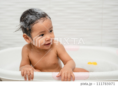 happy infant baby take a bath and playing with foam bubbles in bathtub happy infant baby take a bath and playing with foam bubbles in bathtub 111783071