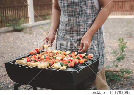 A man grilling pork and barbecue in dinner party. Food, people and family time concept. 111783095